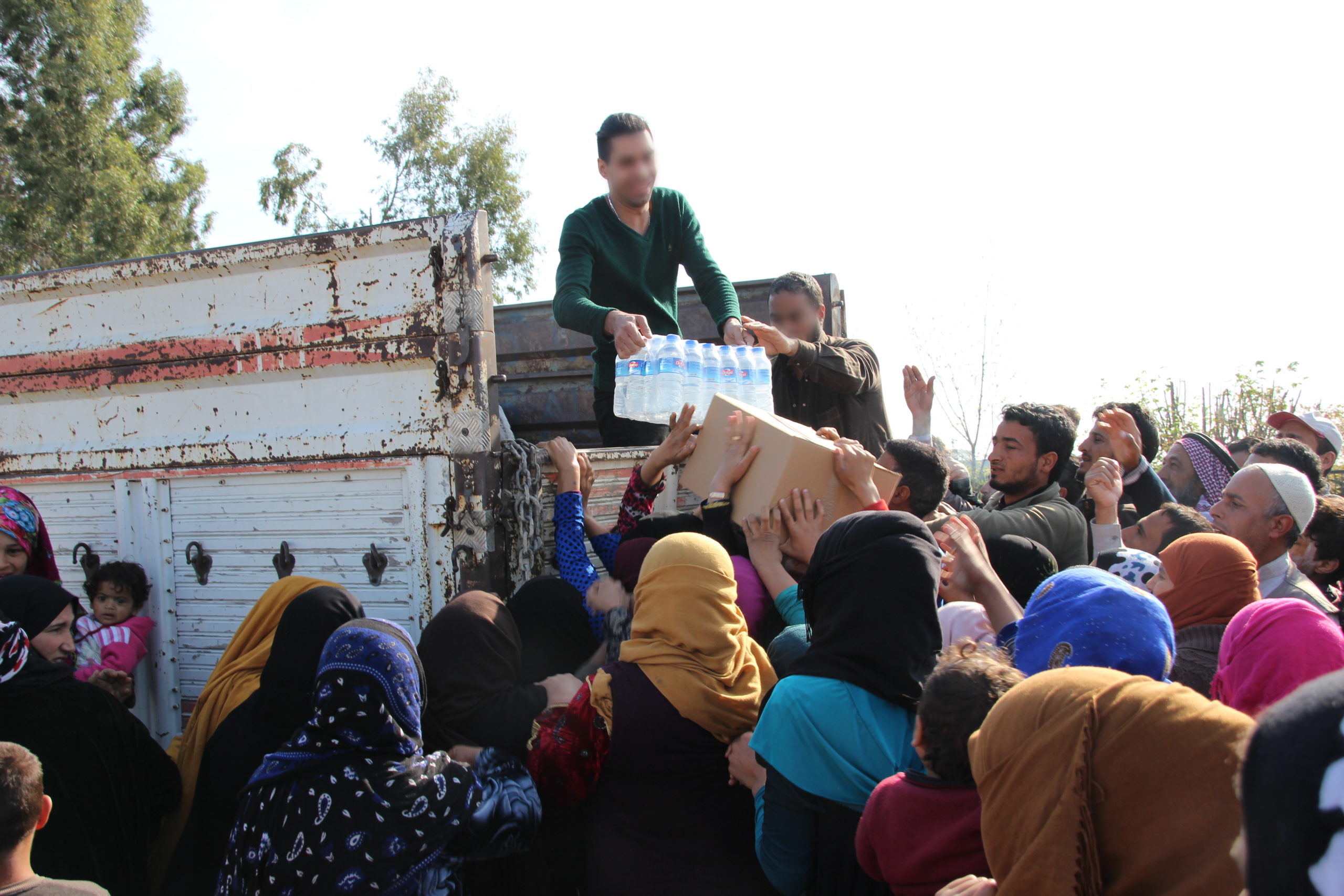 Distributing food and water to refugees living in a tent city